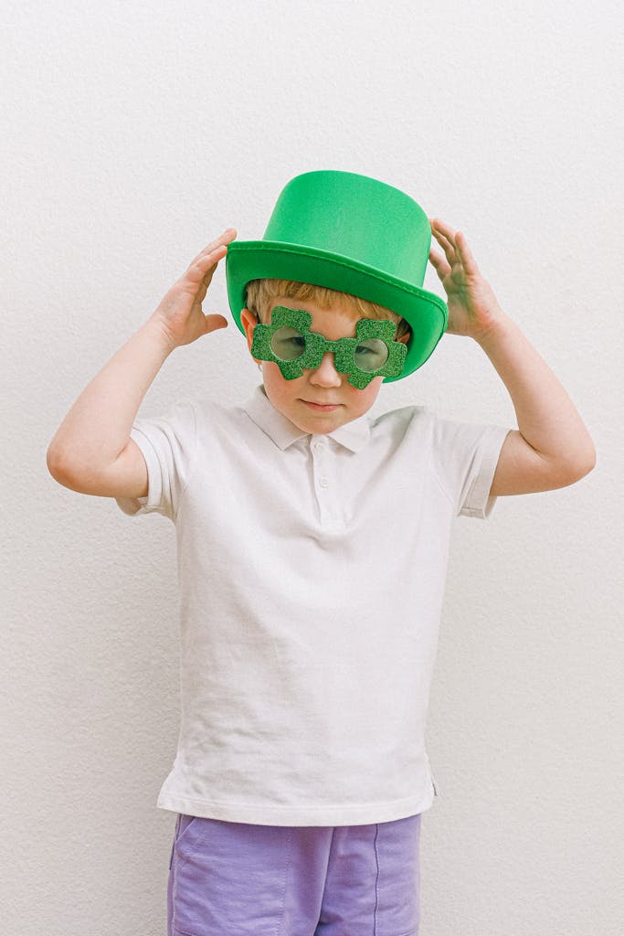 A young boy in a green hat and glasses celebrating St. Patrick's Day.